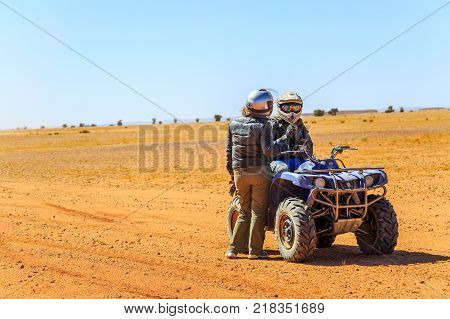 Ait Saoun Morocco - February 23 2016: Men standing by quad bikes in Ait Saoun desert in Morocco on bright day.