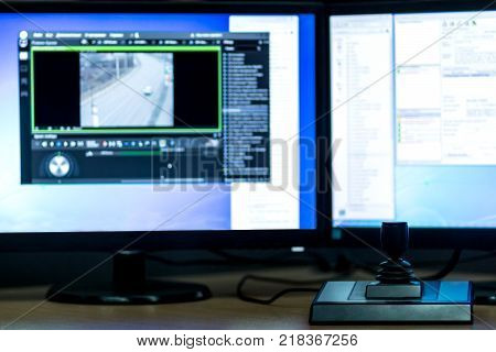 Blurred monitors on the background and joystick controls in the foreground. Workplace for video surveillance.