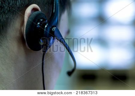 Earphone with microphone headset on man's head against a background of bright monitors close-up.