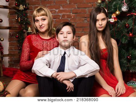 happy family, mother with two children next to cristmas tree in Christmas day.