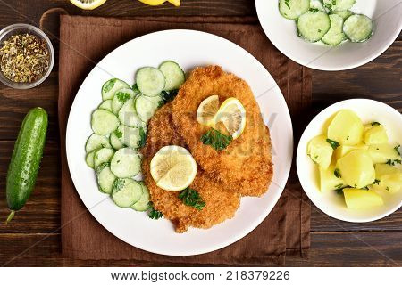Homemade schnitzel with cucumber salad and boiled potato. Top view flat lay food