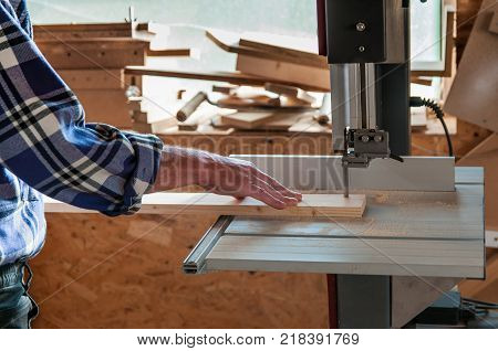 Cutting pine board at the band saw in a small workshop