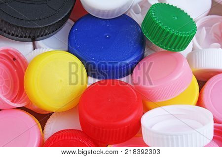 Collect plastic bottle caps. Close-up shot of stack of recyclable plastic bottle caps on white background. Bottle cap texture pattern as background. Colorful plastic cap.