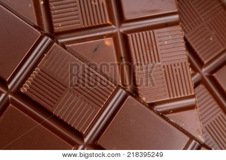 Chocolate bars as background. Milk and dark shiny chocolate texture. Stack chocolates pattern. Stunning beautiful cacao brown dessert sweets.