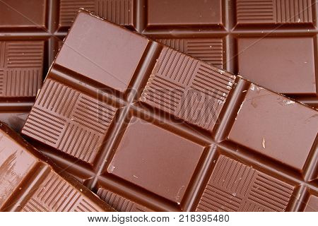 Chocolate bars as background. Milk and dark shiny chocolate texture. Stack chocolates pattern. Stunning beautiful cacao brown dessert sweets.