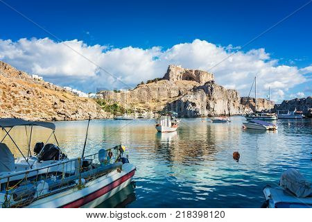 Fishing boats and sail boat in St. Paul´s bay Lindos acropolis in background (Rhodes Greece)