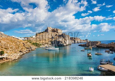 Fishing boats and sail boats in St. Paul´s bay Lindos acropolis in background (Rhodes Greece)