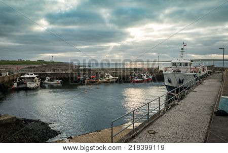 JOHN O'GROATS SCOTLAND - 28 JUNE 2017: A dusk view of the small harbour at John O'Groats Scotland with the Orkney passenger ferry in port.