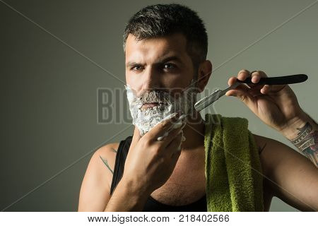 Serious hipster in barbershop new technology. Man cut beard and mustache with razor and shaving brush. Haircut of bearded man archaism. Barber and hairdresser. Fashion and beauty innovation.