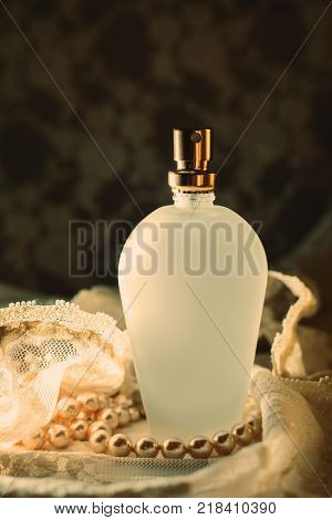 Perfume bottle with white pearls on dark background