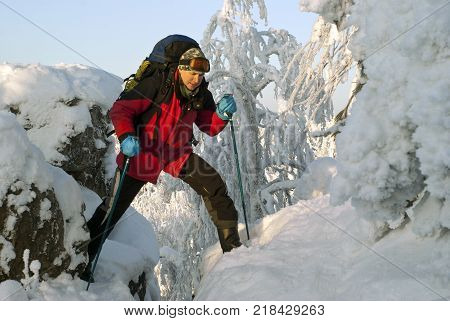 traveler man with a backpack in a beautiful winter mountain landscape oversteps the precipice