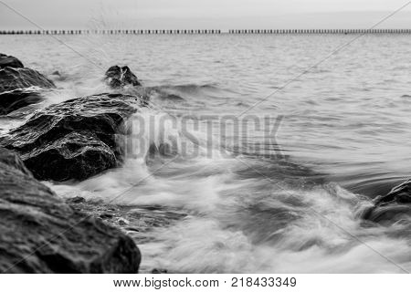 Waves crash over rocks on beach in Essex