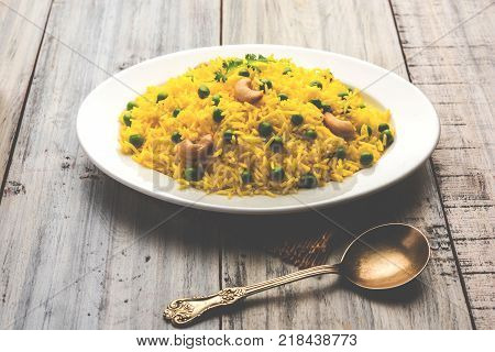Basmati Rice Pilaf or pulav with Peas, or vegetable rice using green peas also known as matar pulav, with added yellow colour, served with plain dal