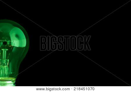 Green , half light bulb isolated on black.