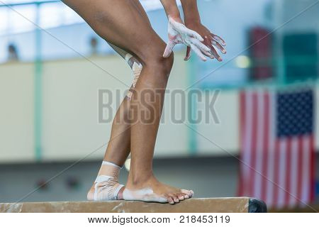 Gymnastics teenager girl closeup hands legs feet ankles bound with tape strapping from injuries on balance beam routine.