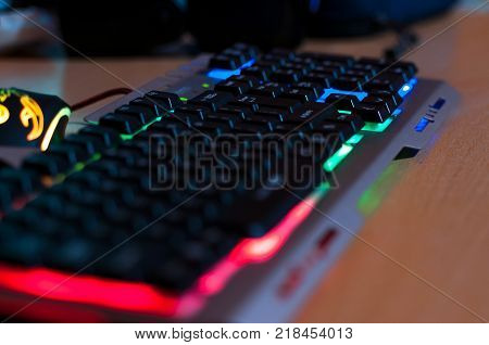 Colorful gaming keyboard, gaming mouse in background.