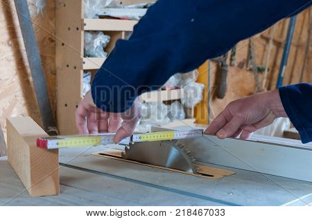 Carpenter taking measurments at the table saw in a small workshop