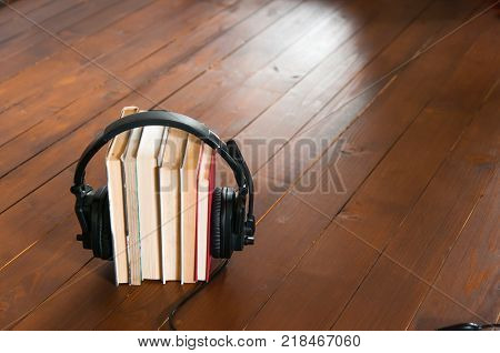 A bunch of book with headphone, audio book conceptual image, on rustic wooden floor.