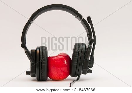 Red, fresh, juicy apple with black headphone isolated on white background.