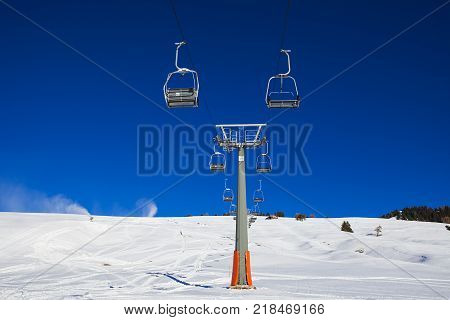 Chairlift without people. The cable car on the blue sky in the Dolomites. Cableway in the mountains without people. Artificial snowing ski by Snow cannon maker. Alpe di Siusi Italy in winter.