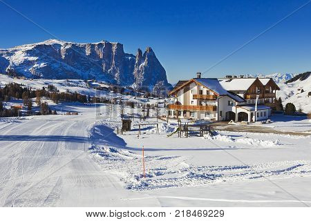 Winter panorama of italian ski resort with background of Seiser Alm Alpe di Siusi a high altitude alpine meadow in Dolomites with Langkofel and Plattkofel mountains under snow South Tyrol Italy.