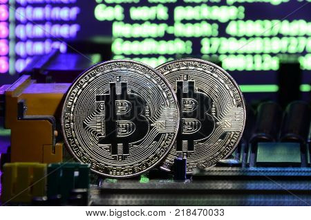 The digital process of cryptocurrency mining by using the GPUs. Bitcoins and video card on a working display and mining screen