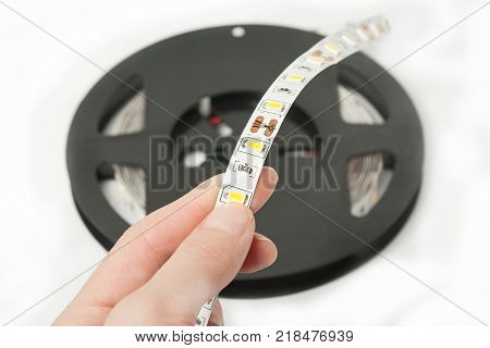 Plastic reel with LED strips for lighting the room.Led lights tape isolated on white background. The hand holds a piece of tape