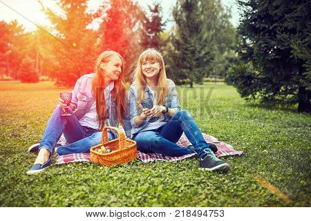 girls couple are sitting in the sunny park. picnik