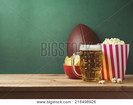 American football watching concept with beer pop corn and chips over green background