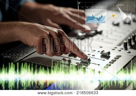 music, technology, people and equipment concept - hands using mixing console in sound recording studio