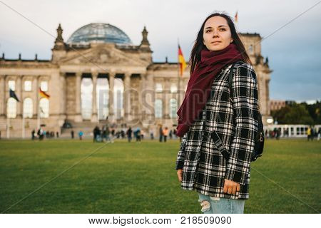 A tourist girl with a backpack next to the building called the Reichstag in Berlin in Germany. Sightseeing, tourism, travel around Europe.
