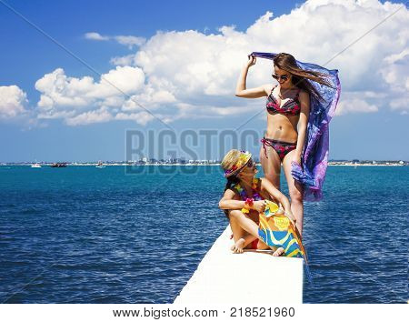Two beautiful women, has haired long hair, red bikini, poreo, sunglasses, slim body, happy smile face. Tropical hot sea.