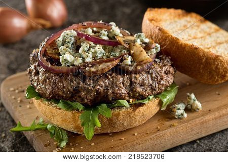 A delicious juicy burger with blue cheese arugula sauteed red onions and muchrooms.