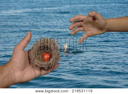 Human hands keep a natural nest with  a red heart inside and a child tries to reach this nest. Family bonds, protection, security, hope, solidarity.