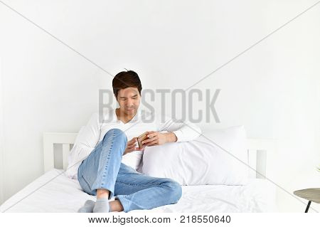Men are playing mobile in the bedroom.