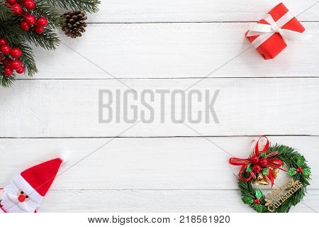 Christmas background. Christmas frame made of fir branches holly berry and red gift box with decoration on white wood board. Creative flat lay top view design.