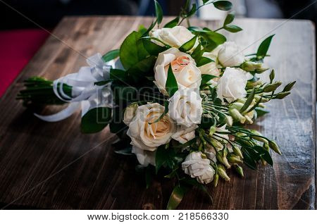 Wedding Rings On The White Roses Laying On Table