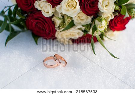 Wedding Rings And Bouquet Lying On The Snow