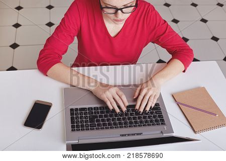 Attractive Female Student With Ginger Hair Bun Thinks About Coursework Strategy, Works With Laptop C