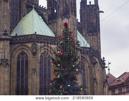 decorated christmas tree with red balls and ribbon in front of prague saint vitus gothic cathedral