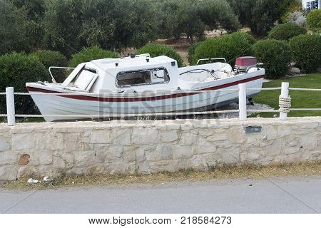Old boat standing on the ground behind the fence.