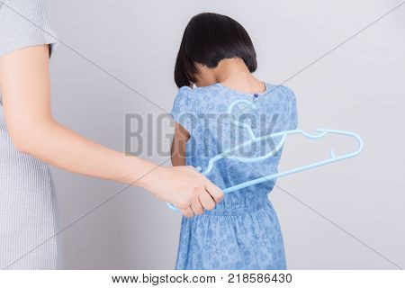 Mother is punishing daughter by hitting with a hanger,Family violence concept