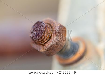 Close-up image of old rusty screw and bolt on steel surface with blurred background