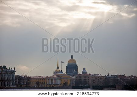 The sun's rays over the historical centre and the river Neva in St. Petersburg. The building of St. Isaac's Cathedral the Admiralty and the Palace bridge in winter.