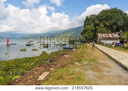 POKHARA NEPAL - September 29 2013: Boats at shoreline of the Phewa lake. Rowboat symbol of Phewa lakeside in Pokhara city.