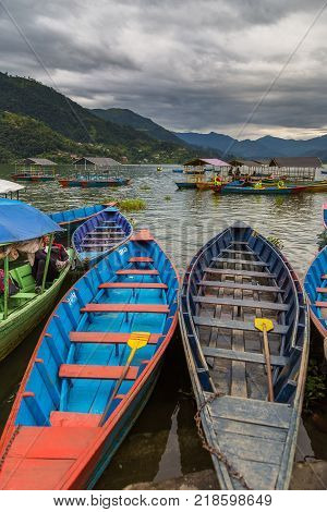 POKHARA NEPAL - September 29 2013: Resident on old small boats sailing on the Phewa lake. Rowboat symbol of Phewa lakeside in Pokhara city.