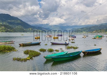 POKHARA NEPAL - September 29 2013: Tourists on old small boats sailing on the Phewa lake. Rowboat symbol of Phewa lakeside in Pokhara city.