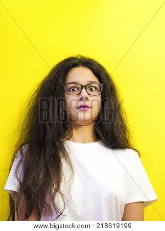 Portrait of a shocked brunette girl looking at camera, isolated on yellow