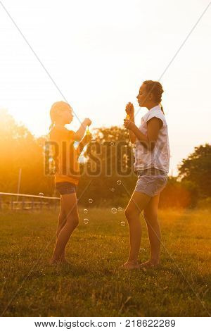 Two teenage girls have fun in the park. Two friends outdoor. Bubble buttle