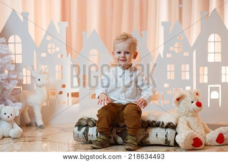 Cute blonde hair little boy near christmas toy paper houses.